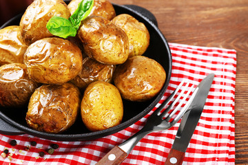 Baked potatoes in pan on wooden table, closeup