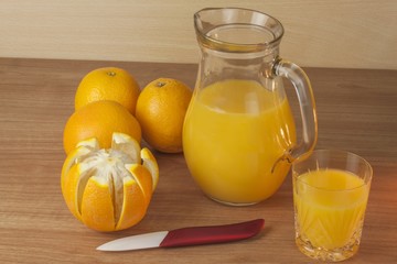 Domestic fresh orange juice in a glass jar on a wooden table. Hand-prepared homemade orange juice. Healthy drink for athletes. Place for your text. Sales of juices.
