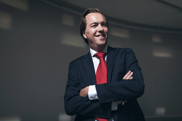 Happy young entrepreneur wearing red tie in empty room.