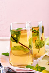Glasses of apple juice with fruits and fresh mint on table close up