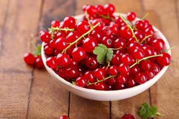 Fresh red currants in bowl on wooden table close up
