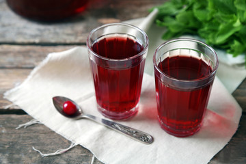 Two glasses with cherry juice on table, on wooden background