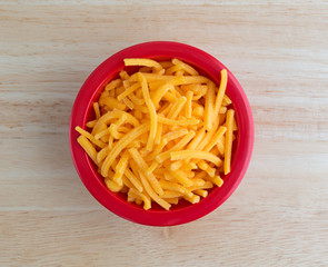 Shredded sharp cheddar cheese in red bowl