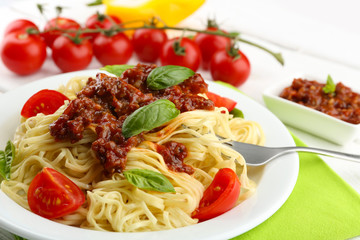 Spaghetti Bolognese on white plate, on color wooden background
