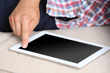 Male hand holding PC tablet on home interior background