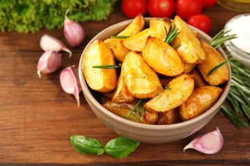 Baked potato wedges on wooden table, closeup