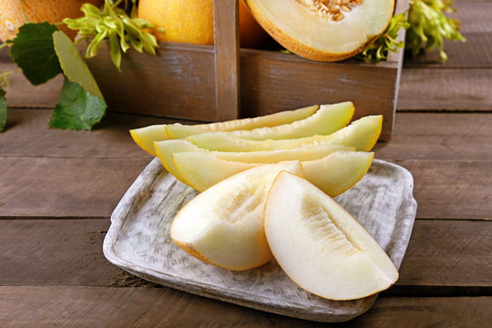 Slices of ripe melons with green leaves on table close up