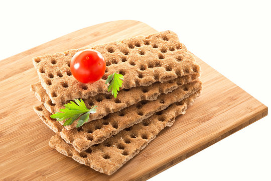 Slices of Crispbread with tomato and parsley on wooden cutting b