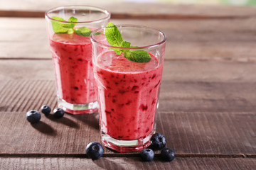 Glasses of berry smoothie on wooden background