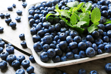Tasty ripe blueberries with mint on wooden table close up