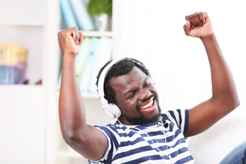 African American man with headphones on sofa in room