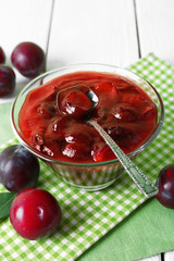Tasty homemade plum jam in glass saucer on checkered napkin, closeup