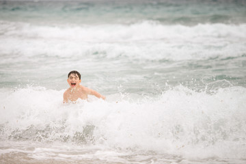 Happy laughing boy is jumping over the sea tides