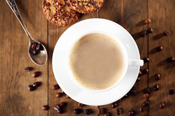 Cup of coffee with cookies and coffee beans on wooden table, top view
