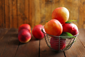 Fresh peaches in wicker basket on wooden background