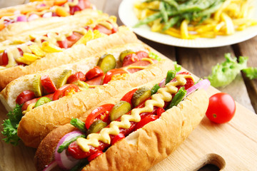 Fresh hot dogs on cutting board and food on plate closeup