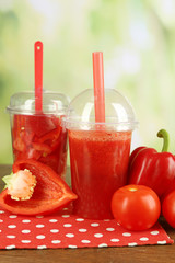 Red vegetable and fruit salad and healthy fresh drink in plastic cups on wooden background. Colorful diet concept