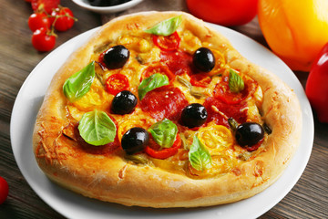 Heart shaped pizza served on plate on wooden background