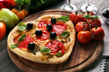 Heart shaped pizza served with wine on wooden table