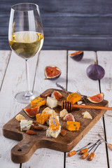 Grape, cheese, figs and honey with a glasses of red and white wine on a wooden Board. Cheese Board.selective focus