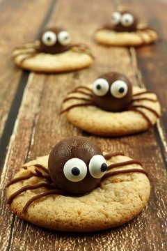 Group of chocolate Halloween spider cookies on rustic old wood