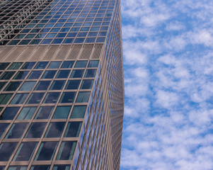 Obraz na płótnie Canvas Facade of glass modern skyscraper with blue sky and white clouds