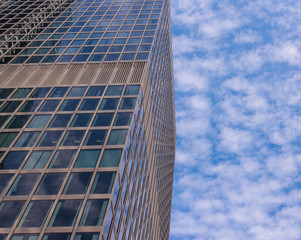 Facade of glass modern skyscraper with blue sky and white clouds