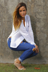 Sexy woman squatting with a concrete wall background