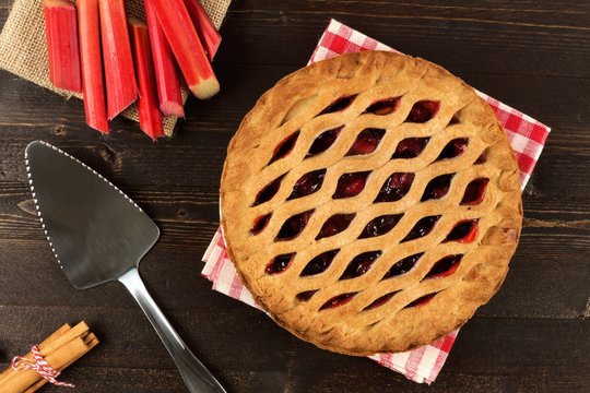 Sweet strawberry and rhubarb pie overhead scene on a dark wooden background