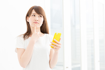 部屋でスマホを見る女性　考える