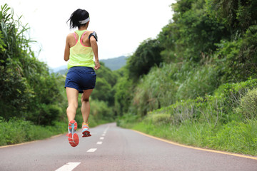 Runner athlete running on forest trail. woman fitness jogging workout wellness concept.