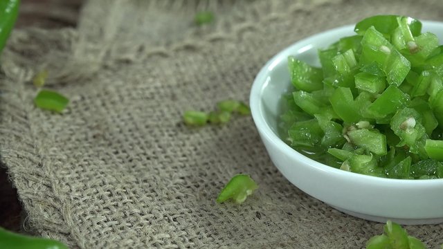 Green Chili chopped on wooden background (seamless loopable 4K footage)