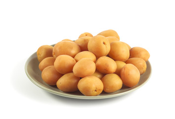 Ripe apricots on a green ceramic plate isolated on white