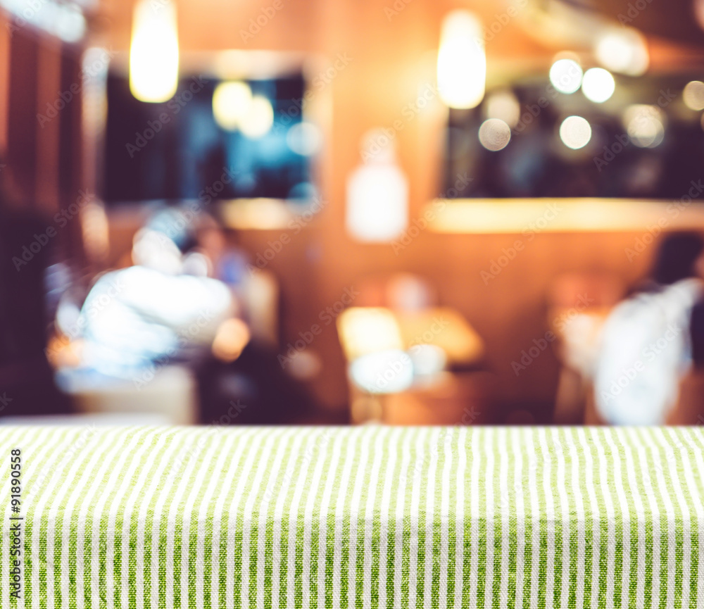 Poster table with green pattern tablecloth with blur restaurant backgro