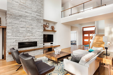 Beautiful furnished living room with hardwood floors, vaulted ceiling, and fireplace in new luxury home