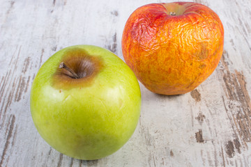 Spoiled apple on old wooden white table