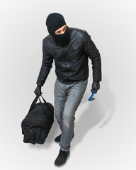 Masked burglar or thief with balaclava is creeping with black balaclava and black bag on white...