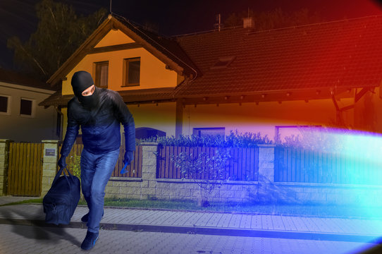 Police lights and runaway masked burglar with balaclava and black bag.