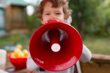 little boy speaking through a red megaphone