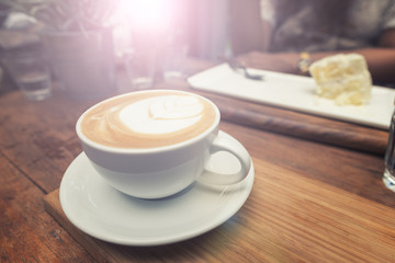 Closeup cup of coffee and women eating cake background.