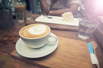 Closeup cup of coffee and women eating cake background.