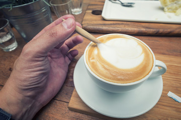 Close up hand mixing with a spoon of coffee in the cup.