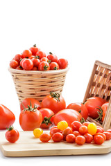 various types of tomatoes on rattan basket and wooden cutting bo