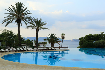 Fototapeta na wymiar Swimming pool on the beach and palm trees