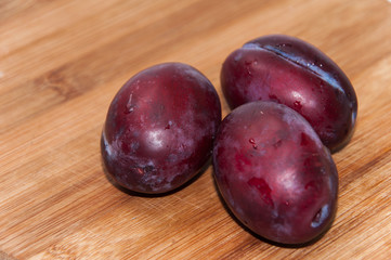 Close view of fresh plums on the wooden board