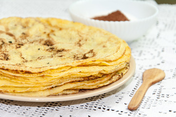 Yellow fresh pancakes served on the plate with cocoa sugar