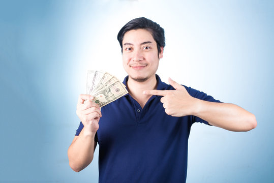 Asian handsome man holding money while standing, on blue backgro