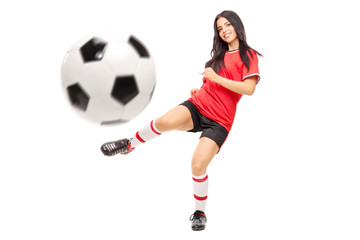 Beautiful female football player shooting a ball