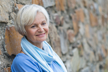 confident natural senior women posing at brick wall