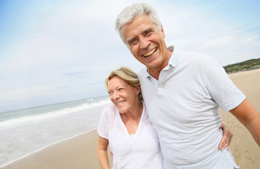 Obraz premium Married senior couple having fun walking in the beach